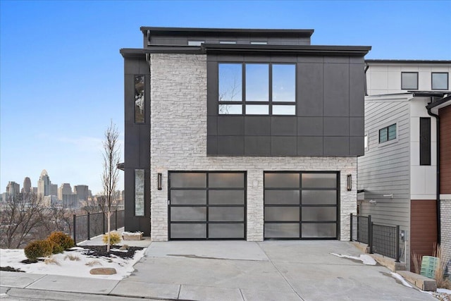 modern home with a garage, stone siding, and concrete driveway