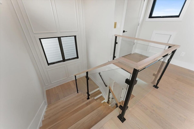 staircase featuring wood finished floors and a decorative wall