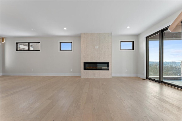 unfurnished living room featuring a large fireplace, baseboards, light wood-style floors, and recessed lighting