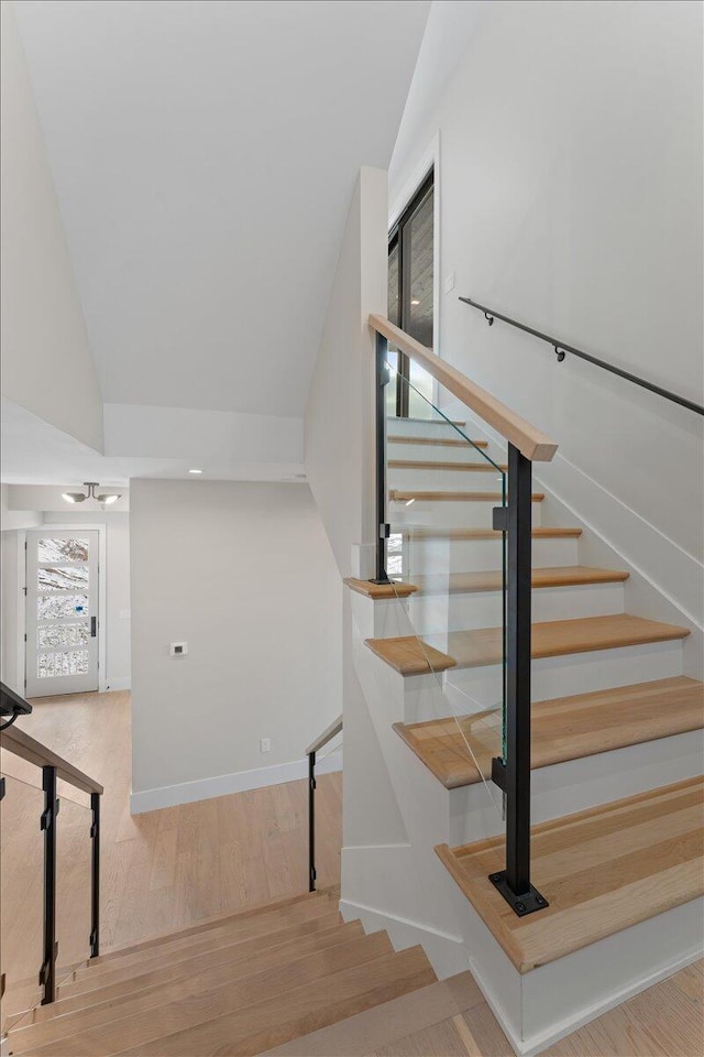 stairs with lofted ceiling, baseboards, and wood finished floors