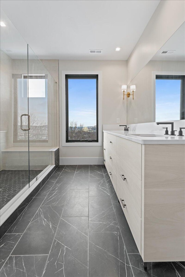 full bath with marble finish floor, double vanity, visible vents, a stall shower, and baseboards