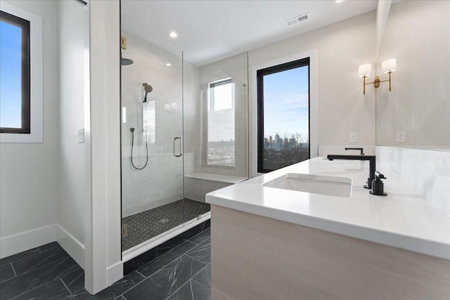 full bathroom featuring double vanity, a stall shower, baseboards, visible vents, and a sink