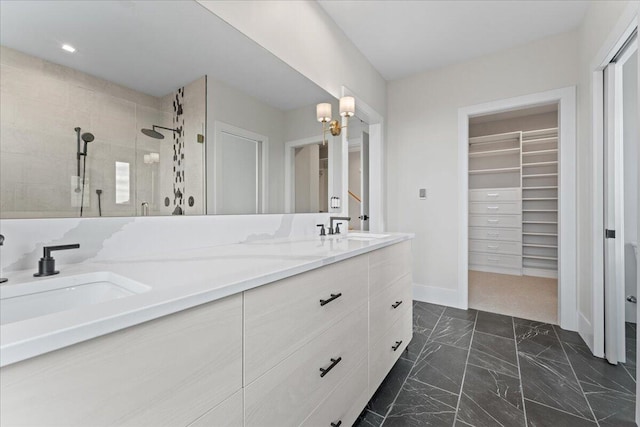 full bathroom with double vanity, a stall shower, a spacious closet, and a sink