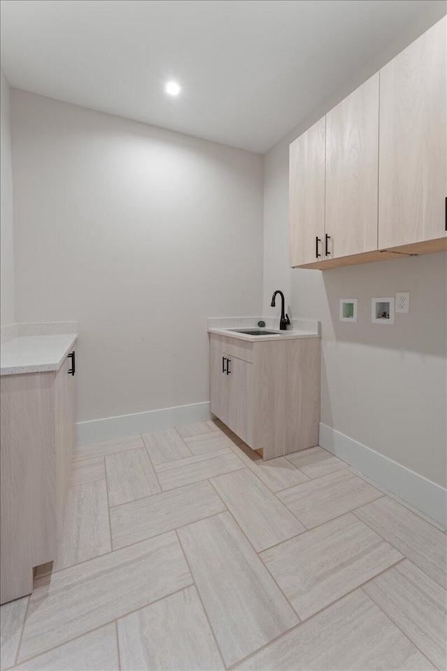 clothes washing area featuring cabinet space, baseboards, washer hookup, and a sink