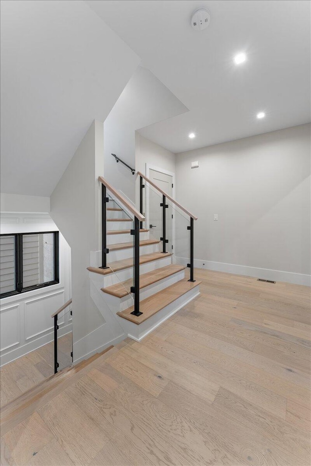 stairs with wood finished floors, visible vents, and baseboards