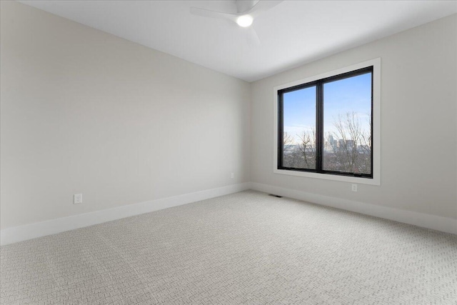 empty room with light carpet, visible vents, a ceiling fan, and baseboards