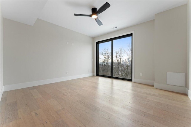 unfurnished room with light wood-type flooring, baseboards, visible vents, and ceiling fan