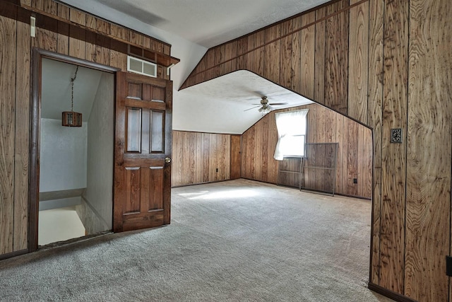 bonus room featuring visible vents, lofted ceiling, wooden walls, and carpet flooring