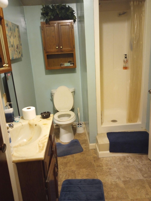 bathroom with baseboards, toilet, a stall shower, and vanity