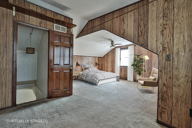 carpeted bedroom with wooden walls, lofted ceiling, and visible vents