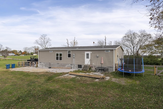 back of house with a trampoline, entry steps, crawl space, and a lawn