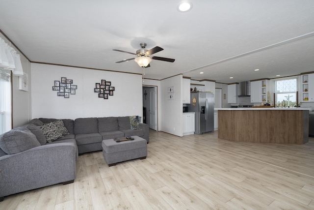 living room featuring light wood finished floors, ceiling fan, and crown molding