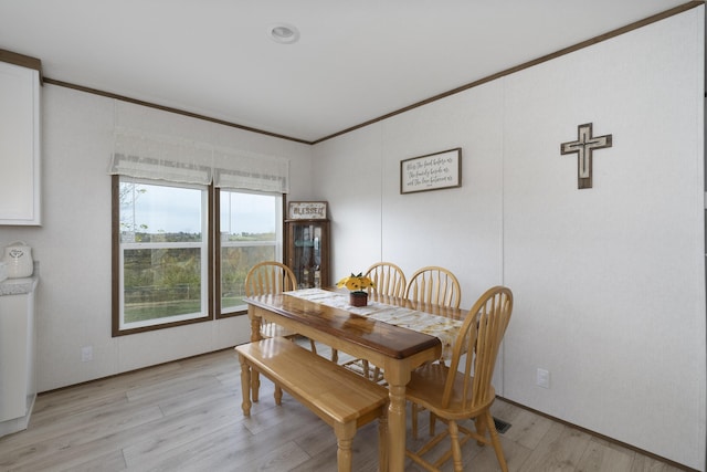 dining area featuring light wood finished floors and ornamental molding