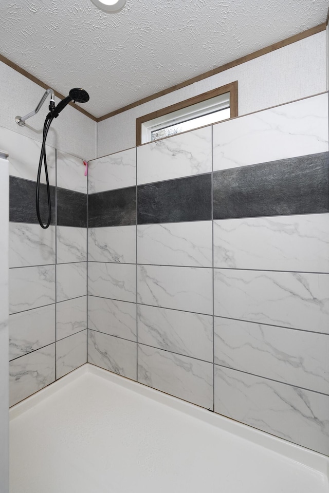 bathroom with a textured ceiling and a tile shower