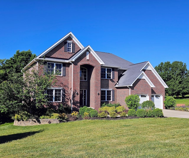 view of front of house featuring an attached garage, a front lawn, concrete driveway, and brick siding