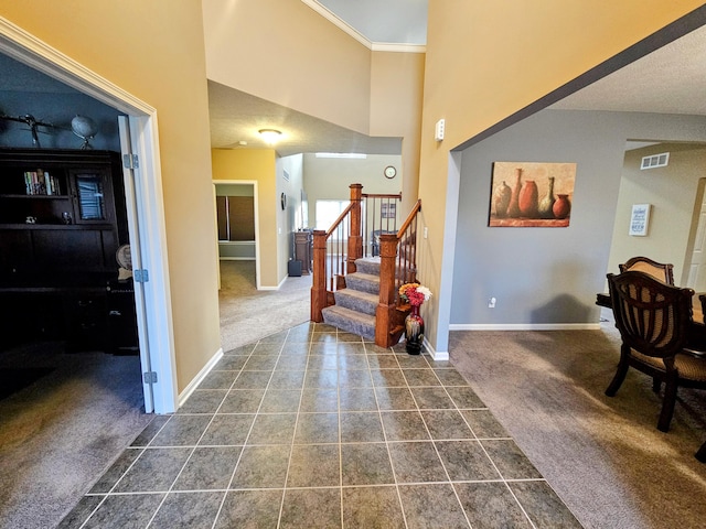 entryway with baseboards, visible vents, dark carpet, and a high ceiling