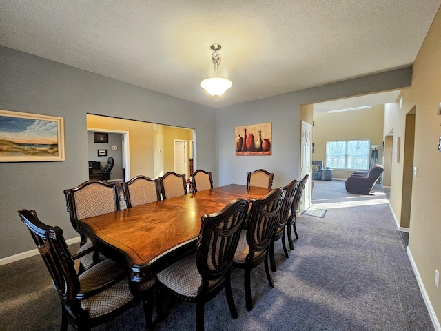 dining space featuring a textured ceiling, dark carpet, lofted ceiling, and baseboards