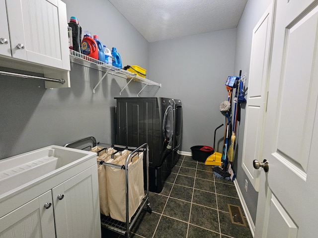 laundry room featuring cabinet space, visible vents, a textured ceiling, separate washer and dryer, and dark tile patterned floors