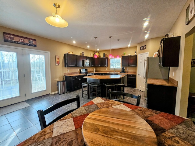 tiled dining space featuring a sink, a textured ceiling, and recessed lighting