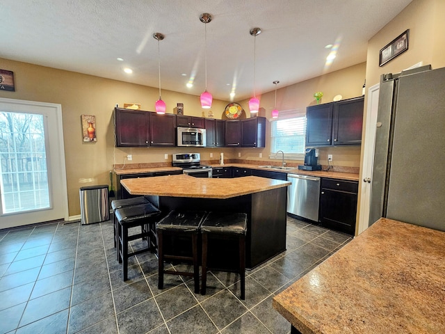 kitchen with a center island, a breakfast bar area, light countertops, appliances with stainless steel finishes, and a sink