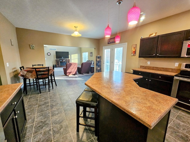 kitchen featuring a kitchen breakfast bar, a center island, light countertops, french doors, and stainless steel range with electric stovetop