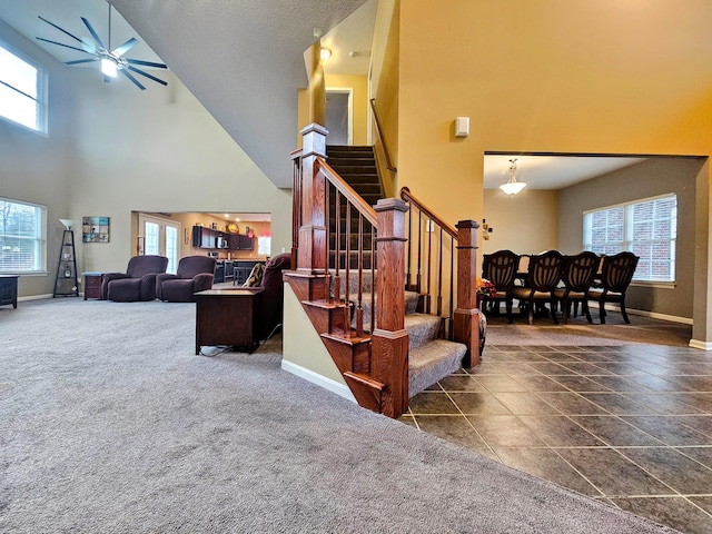 stairway featuring carpet floors, baseboards, a high ceiling, and a ceiling fan