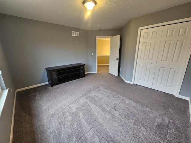 unfurnished bedroom with a textured ceiling, a closet, carpet flooring, and baseboards