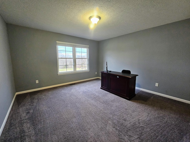 unfurnished office with visible vents, dark carpet, a textured ceiling, and baseboards