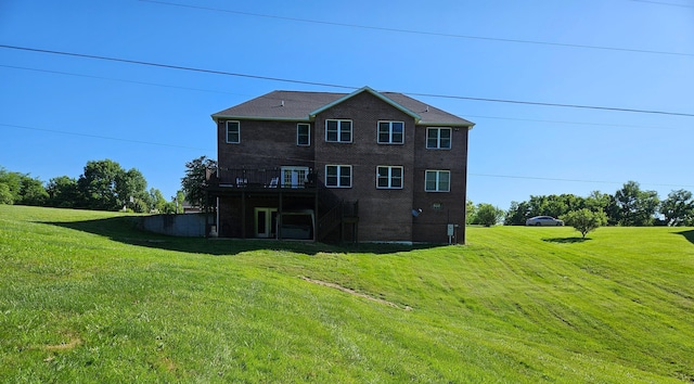 back of property with brick siding, a yard, and a deck