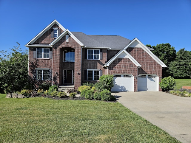 colonial inspired home with driveway, brick siding, a garage, and a front yard