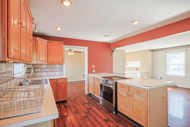 kitchen with dark wood finished floors, light countertops, backsplash, stainless steel range with electric cooktop, and a sink