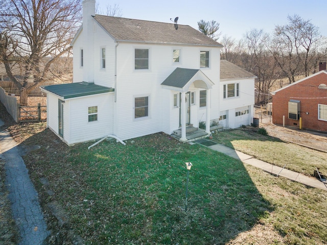 rear view of property with a garage, a shingled roof, fence, a lawn, and a chimney