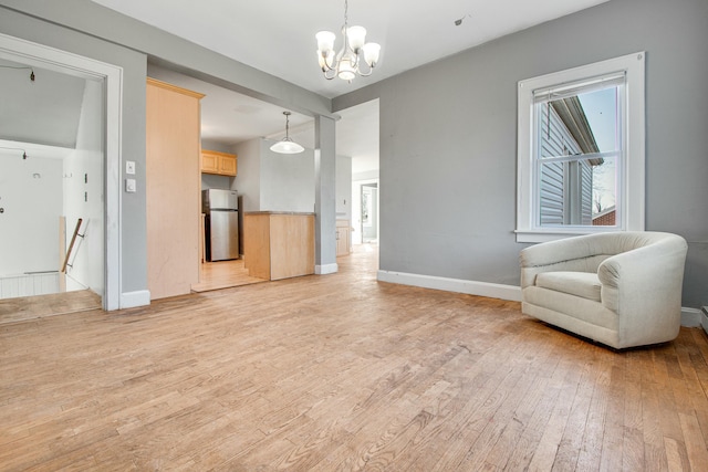 living room with a chandelier, light wood-style flooring, and baseboards