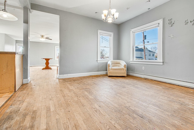 unfurnished room with ceiling fan with notable chandelier, baseboard heating, light wood-type flooring, and baseboards