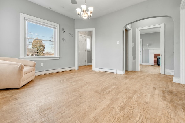 unfurnished room featuring arched walkways, a baseboard radiator, a baseboard heating unit, light wood-style floors, and a brick fireplace