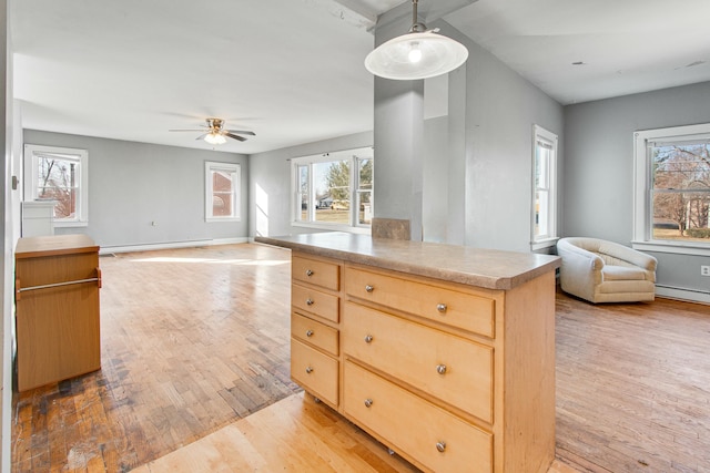 kitchen with light wood finished floors, baseboards, open floor plan, baseboard heating, and light brown cabinets