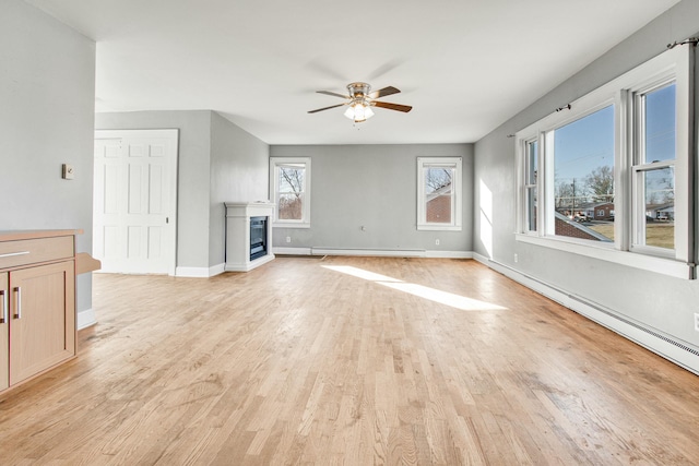 unfurnished living room with a baseboard radiator, a ceiling fan, baseboards, light wood-style floors, and a glass covered fireplace