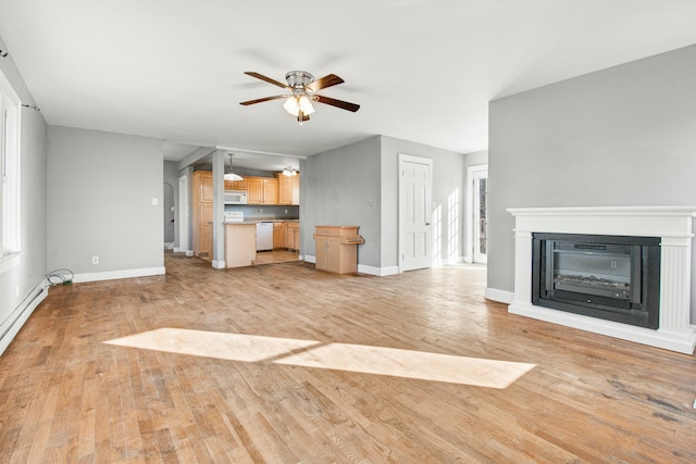 unfurnished living room featuring light wood-style floors, ceiling fan, baseboards, and a glass covered fireplace