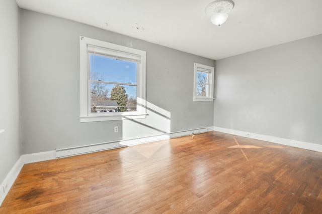 empty room with baseboards, baseboard heating, and wood finished floors