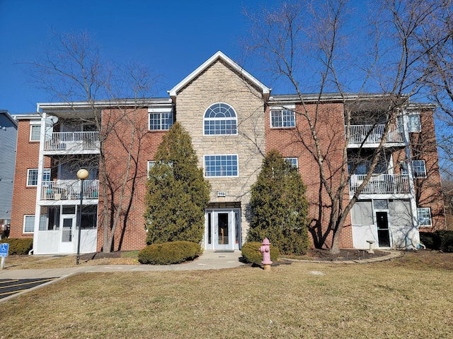 view of front of house featuring stone siding, a front lawn, and brick siding