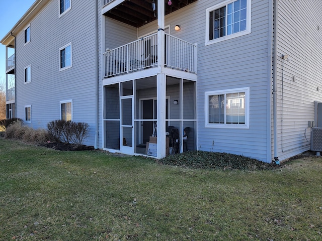 rear view of property with a sunroom and a lawn