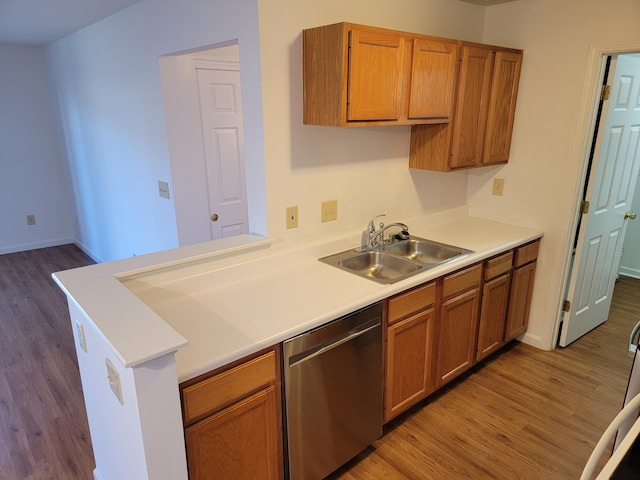 kitchen featuring dishwasher, wood finished floors, brown cabinetry, and a sink