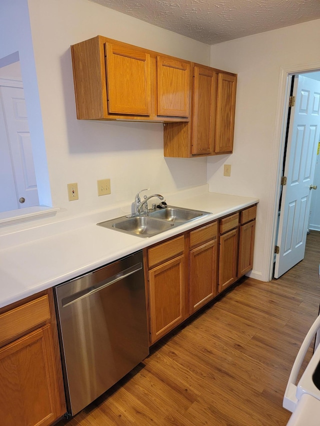 kitchen featuring brown cabinets, a sink, light wood-style flooring, and stainless steel dishwasher