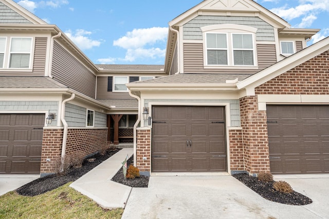 view of front of house with a garage, concrete driveway, brick siding, and roof with shingles