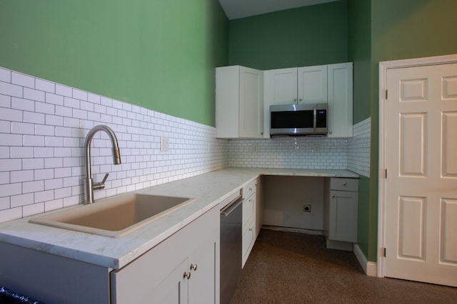 kitchen featuring appliances with stainless steel finishes, white cabinets, a sink, and backsplash
