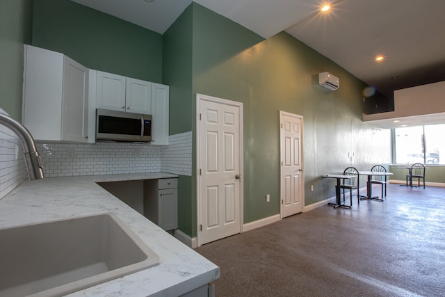 kitchen featuring light stone countertops, a high ceiling, stainless steel microwave, and a sink