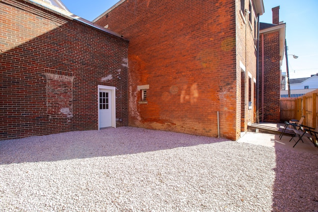 back of property with brick siding, fence, and a patio