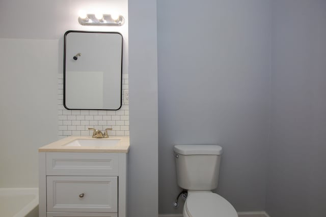 bathroom featuring toilet, a tub to relax in, backsplash, and vanity