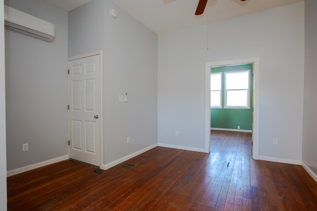 unfurnished room with dark wood-style floors, visible vents, a ceiling fan, a wall mounted air conditioner, and baseboards