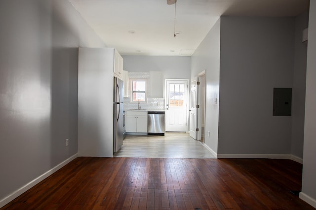 kitchen with white cabinets, light wood-style flooring, appliances with stainless steel finishes, backsplash, and a sink
